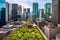 green rooftops surrounded by towering skyscrapers and bustling city streets