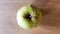 Green rotten apple on a wood background. Green apple on a old wooden background, top view. Organic juicy bio apple ugly, with