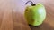 Green rotten apple on a wood background. Green apple on a old wooden background, top view. Organic juicy bio apple ugly, with