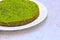 Green round spinach mint cake on a white plate on a concrete background