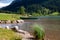 .Green rowboat on the beach of a romantic mountain lake with stones in the foreground and mountains in the background