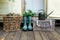 Green rubber boots, watering can and wicker baskets. Cozy decor of autumn terrace of house. Garden boots.