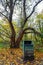 A green rubbish bin trash can with tree in Harvington Park, Beckenham, Kent, UK