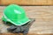 Green safety helmet and gauntlet cloves on a wooden background.
