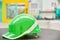 Green safety helmet on industrial background.