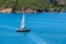 Green Sailboat with White Sail on Blue Water