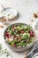 Green salad with feta cheese, arugula, mushrooms, walnut in ceramic bowl on textured background. Healthy summer lunch or