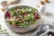Green salad with feta cheese, arugula, mushrooms, walnut in ceramic bowl on textured background. Healthy summer lunch or