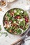 Green salad with feta cheese, arugula, mushrooms, walnut in ceramic bowl on textured background top view. Healthy summer