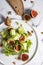 Green salad with figs on white plate and white marble patterned background