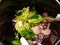 Green salad with red onion and raddish in black bowl closeup photo