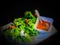 Green salad wrapped shrimp in dark scene