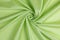 The green satin fabric is laid in a spiral view. Soft folds of a drapery