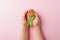 Green satin ribbon holding in kids hands on pink background. Liver, kidney cancer awareness, Glaucoma Awareness