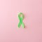 Green satin ribbon on pink background. Liver, kidney cancer awareness, Glaucoma Awareness