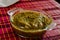 Green sauce made with green tomato, serrano chile, chiltepin chile, on a transparent glass plate.