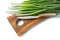 Green scallions stems and kitchen knife on wooden chopping board isolated