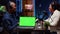 Green screen laptop next to man on podcast discussing with guest during marathon stream