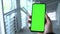 Green screen smartphone. A man`s hand holds a phone. Scrolling on the green screen of the phone. Smartphone footage.
