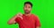 Green screen, thumbs down and face of onfused Asian man with doubt, decision and choice in studio. Unsure, hand sign and