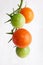 Green and semi ripe cherry tomatoes on vine macro shot isolated on white