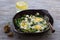 Green shakshuka with spinach, leek and feta in a ceramic frying pan