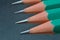 Green sharpened wooden pencils with black lead on a dark textured background. close-up