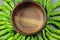 Green Shishito peppers in a circle with an empty wooden bowl in the center