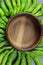 Green Shishito peppers in a circle with an empty wooden bowl in the center