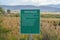 Green sign board with Park Rules against lush tall grasses on a vast terrain