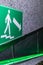 Green sign on the wall pointing the arrow towards the door to exit to a safe place in case of fire and emergency