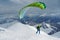 Green skier starts with a paraglider in highlands