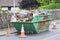 Green skip and cones outside house on road full of waste and rubbish to recycle