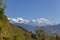 Green slope of a hill against the backdrop of a snowy mountain of Annapurna under a clear blue sky