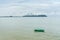 Green small fishng boat parked at the shore of Prachuap Bay with fog on Khao Ta Mong Lai Forest Park background, Thailand