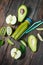 Green smoothie in bottl with avocado, apple and kiwi on white wooden background