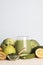 green smoothie in glass, spirulina powder, vegetables and fruits on blue background.