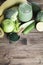 green smoothie in glass, spirulina powder, vegetables and fruits on wooden background.