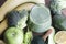 green smoothie in glass, spirulina powder, vegetables and fruits on wooden background.