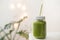 Green smoothie in a mason jar with white lead and recycled paper straw. Summer refreshments. Spinach and cucumber smoothie