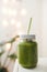 Green smoothie in a mason jar with white lead and recycled paper straw. Summer refreshments. Spinach and cucumber smoothie