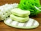 Green soap bar and plastic bath puff on wooden background