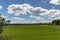 Green soccer field under blue sky with white clouds