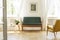 Green sofa with dark, wooden frame and a comfy yellow armchair i