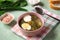 Green soup in a bowl. Sorrel soup with eggs and leaves, onion, bread on a green table.