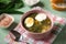 Green soup in a bowl. Sorrel soup with eggs and leaves, onion, bread on a green table.