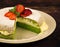 Green spinach cake with strawberry and mint on a dark rustic wooden background