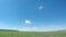 Green spring field and small clouds.