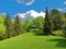 Green spring landscape with bench under sun umbrella idyll