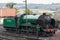 A green steam train on railway tracks